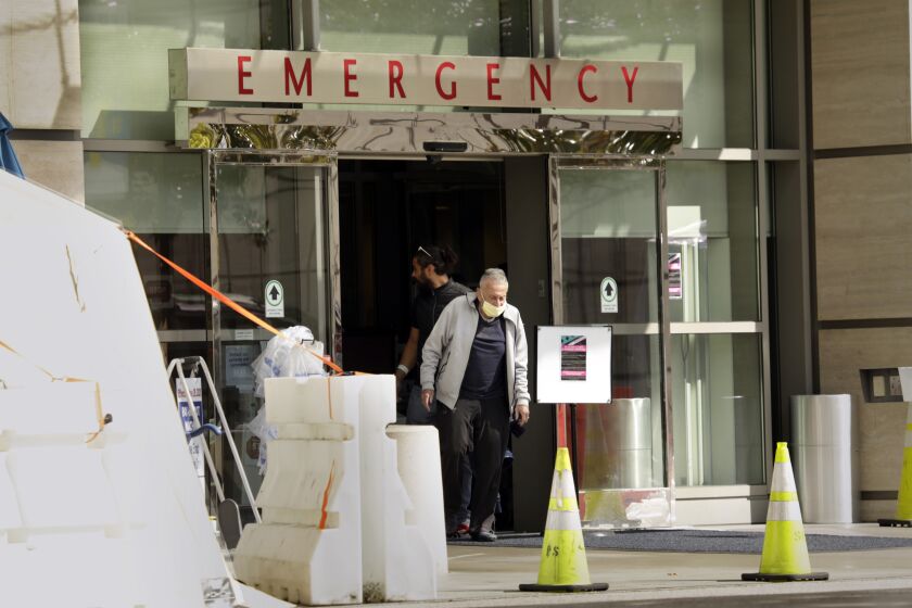 LOS ANGELES, CALIFORNIA-MARCH 18, 2020-At UCLA Medical Center, an elderly man leaves the emergency room with a mask on outside the temporary testing area. Testing for Covid-19 is going on at UCLA Medical Center. (Carolyn Cole/Los Angeles Times)