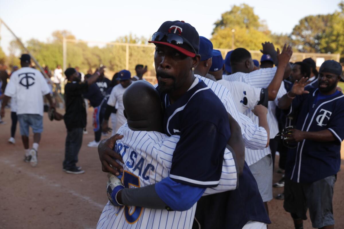 Twins and Brewers players embrace each other at the Crips softball championship. The Brewers represent the 40s neighborhood and the Twins represent the 30s neighborhood of South Los Angeles.