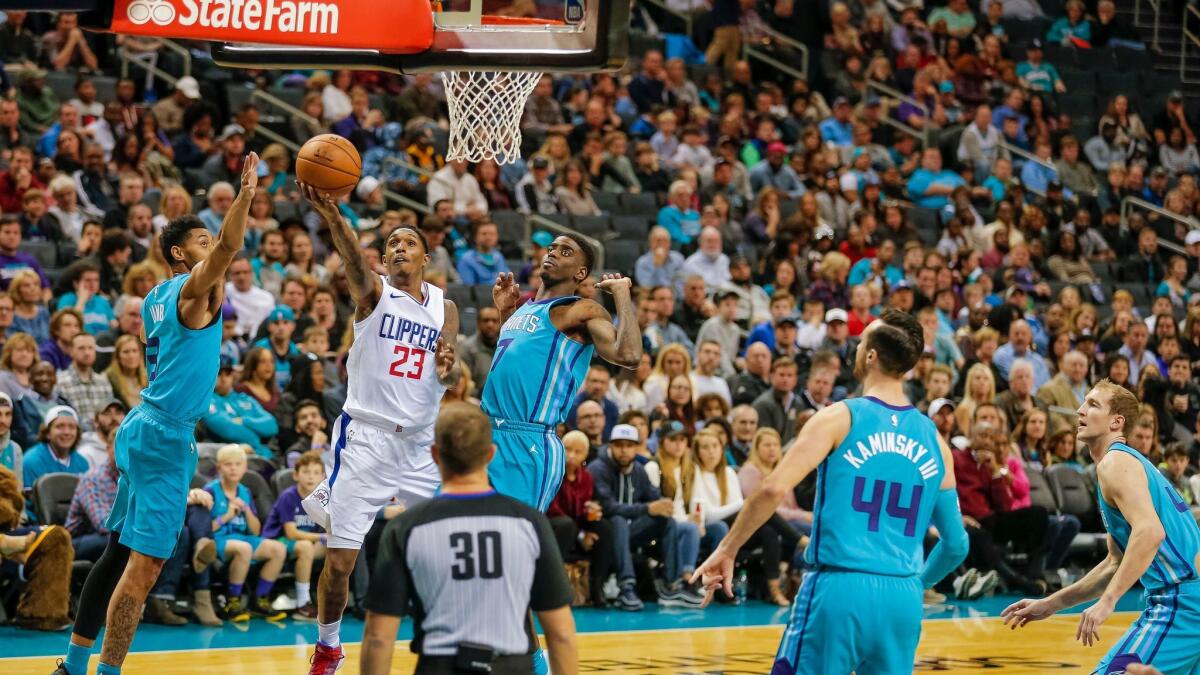 The Clippers' Lou Williams gets a shot off in between Charlotte 's Jeremy Lamb and Dwayne Bacon during the first half Sunday.