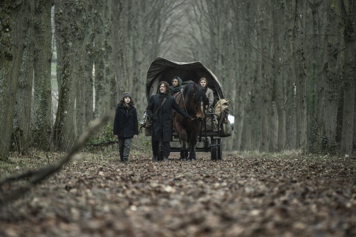 On a tree-lined road, a man leads a boy and two nuns in a wagon on a trek across France in "The Walking Dead: Daryl Dixon." 