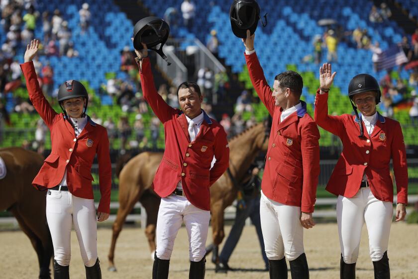 U.S. equestrians Lucy Davis, from left, Kent Farrington, McLain Ward and Elizabeth Madden celebrate after winning a silver medal in the team jumping competition.