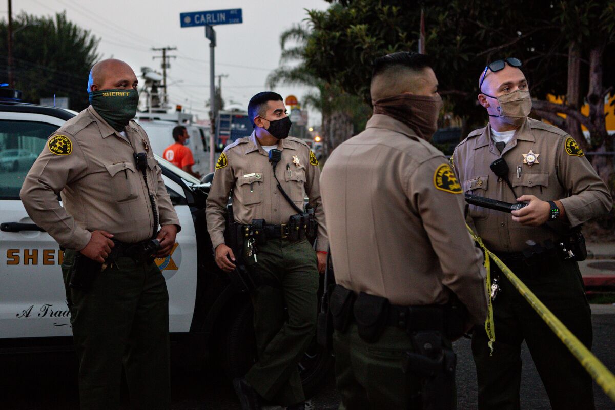 Los Angeles County sheriff's deputies wear masks as they block a Lynwood street during a search for a carjacking suspect.