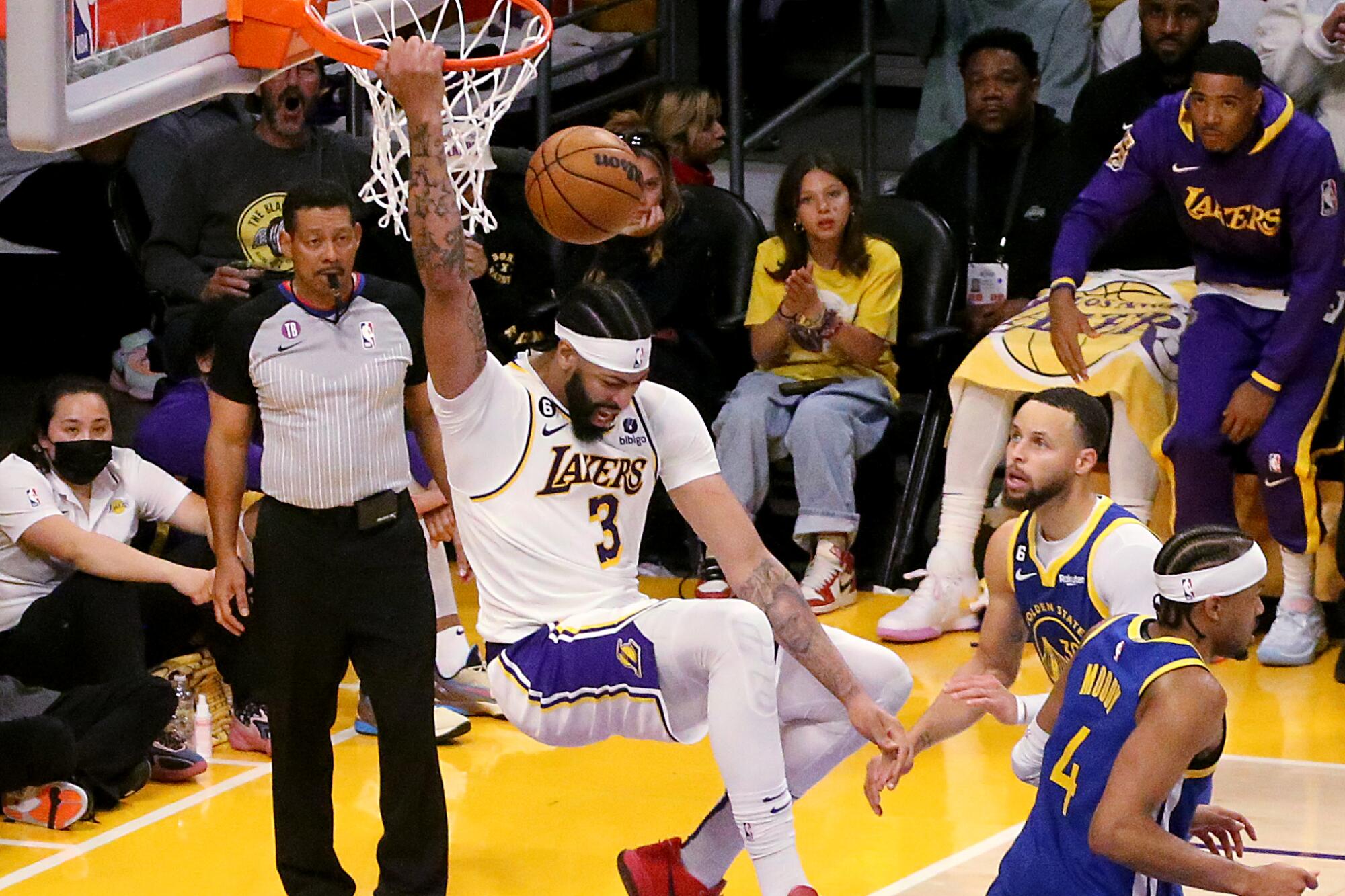 Lakers power forward Anthony Davis hangs on the rim after throwing down a dunk against the Warriors.