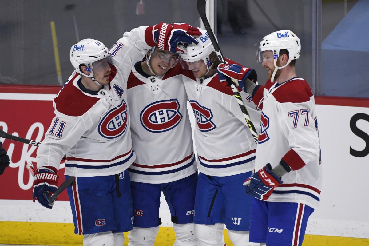 Montreal Canadiens' Brendan Gallagher (11), Nick Suzuki (14), Tyler Toffoli (73) and Brett Kulak (77) celebrate Toffoli's goal during second-period NHL hockey game action against the Winnipeg Jets in Winnipeg, Manitoba, Monday, March 15, 2021. (Fred Greenslade/The Canadian Press via AP)