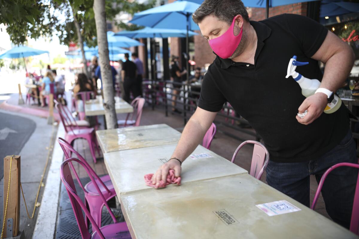 A waiter cleans a table at Breakfast Company in the Gaslamp Quarter in downtown San Diego.