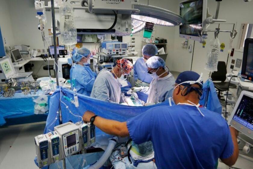 Dr. Andrew Lowy, center, performs a pancreatectomy for a pancreatic tumor at the Jacobs Medical Center at UC San Diego Health on Nov. 28, 2018. From left are, surgical tech Kathleen Naughton, medical student Brendan Cronin, Shanglei Liu, MD, resident physician, and Edward Orestes O'Brien, MD, anesthesiologist, right. (Photo by K.C. Alfred/San Diego Union-Tribune)