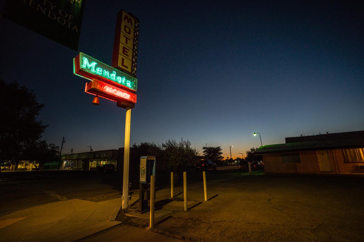 A motel sign illuminates the main drag as the sun sets in Mendota, Calif.