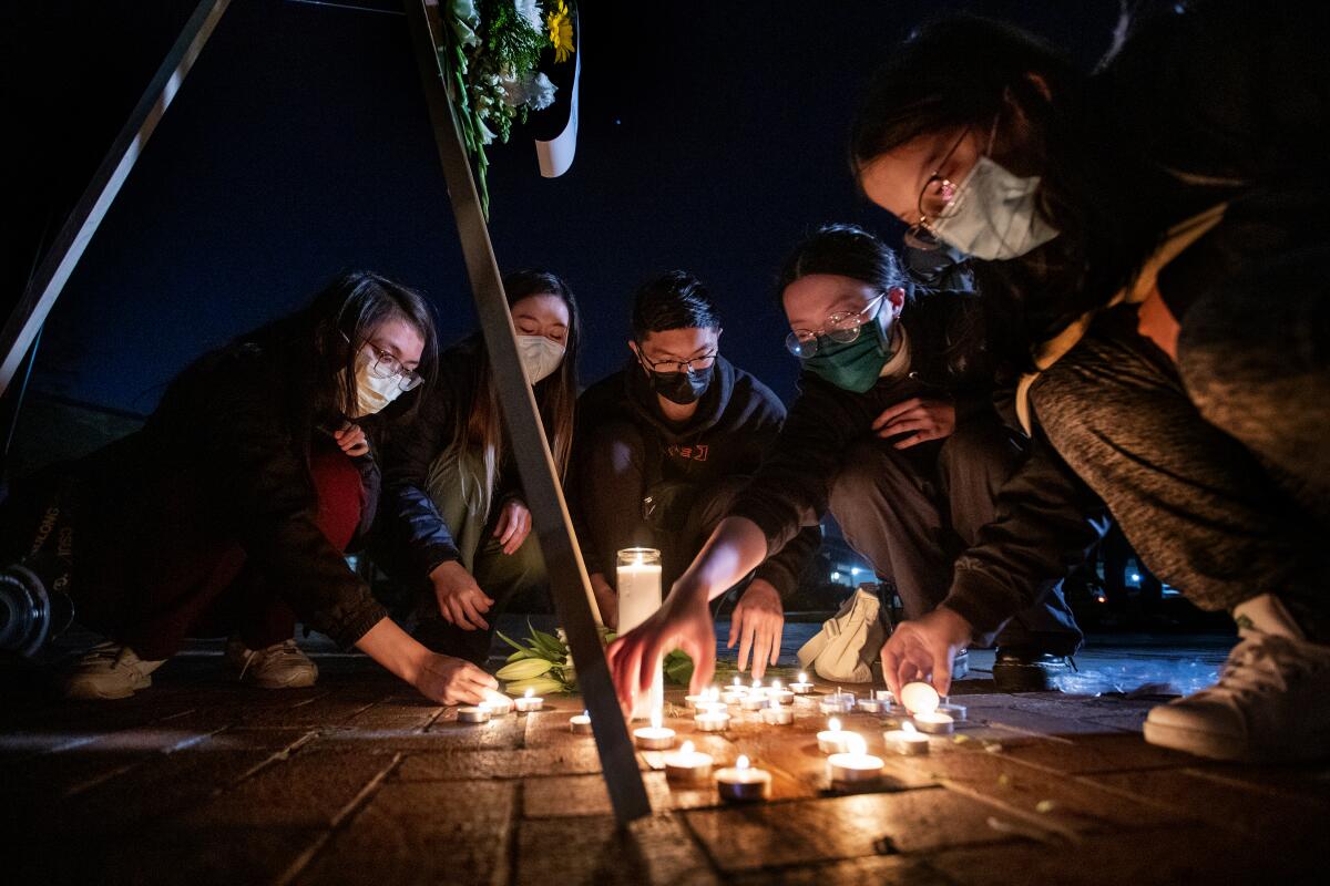 People light candles in a heart shape at a nighttime vigil 