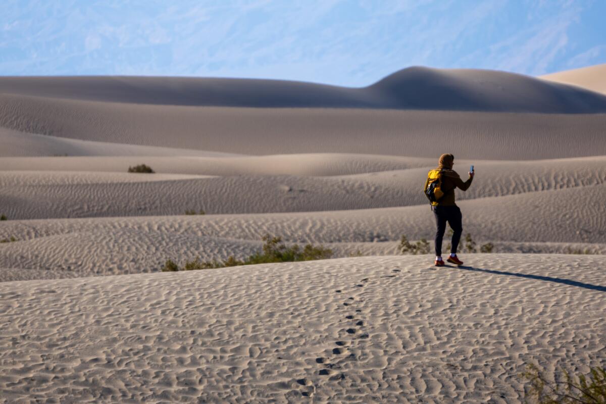 A man hikes in sandy dunes