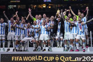 Argentina's Lionel Messi holds up the trophy in front of his teammates after winning the World Cup