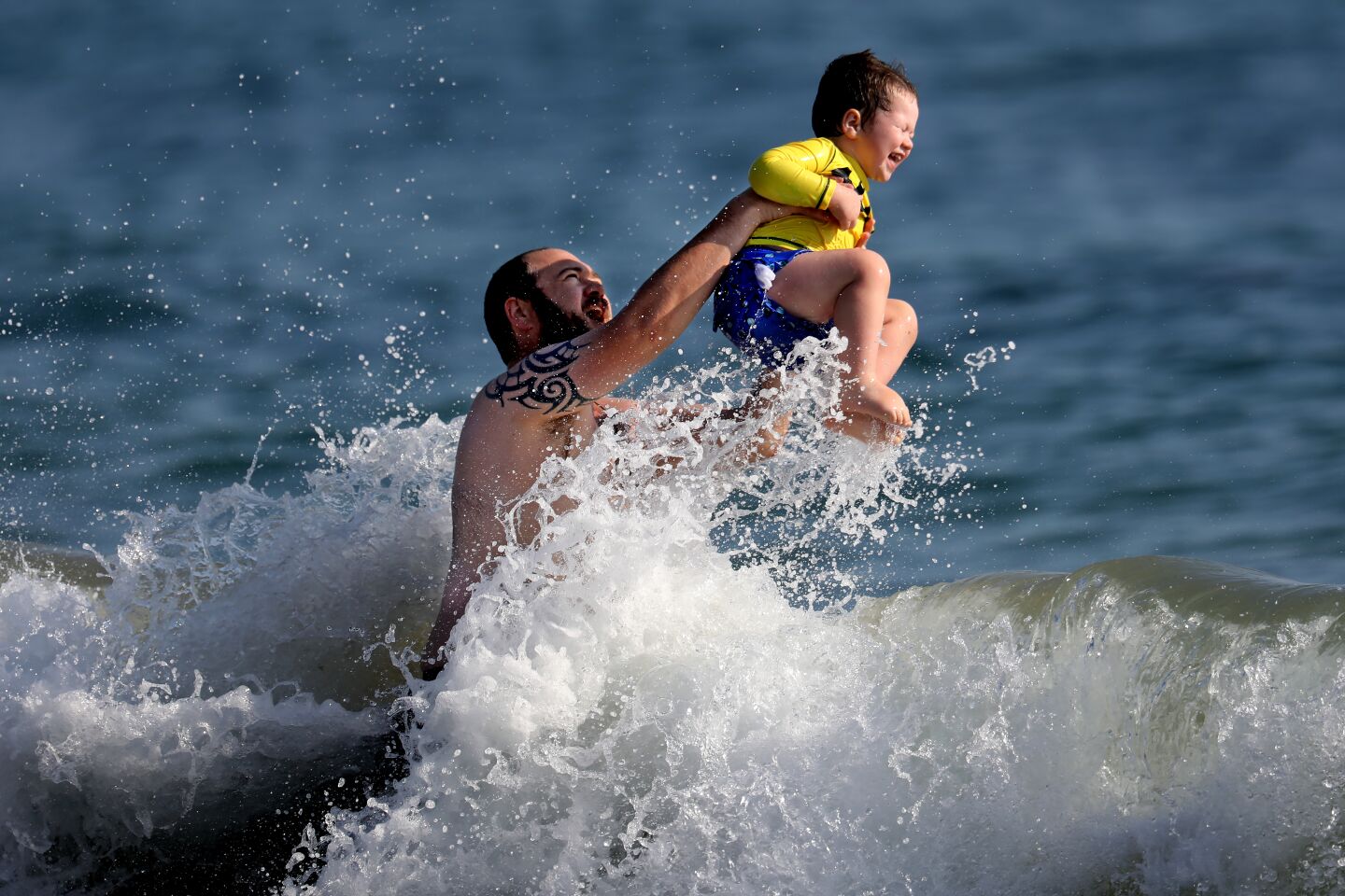 Cael Kirkland of Los Angeles and his son cool off at Will Rogers State Beach on Friday.