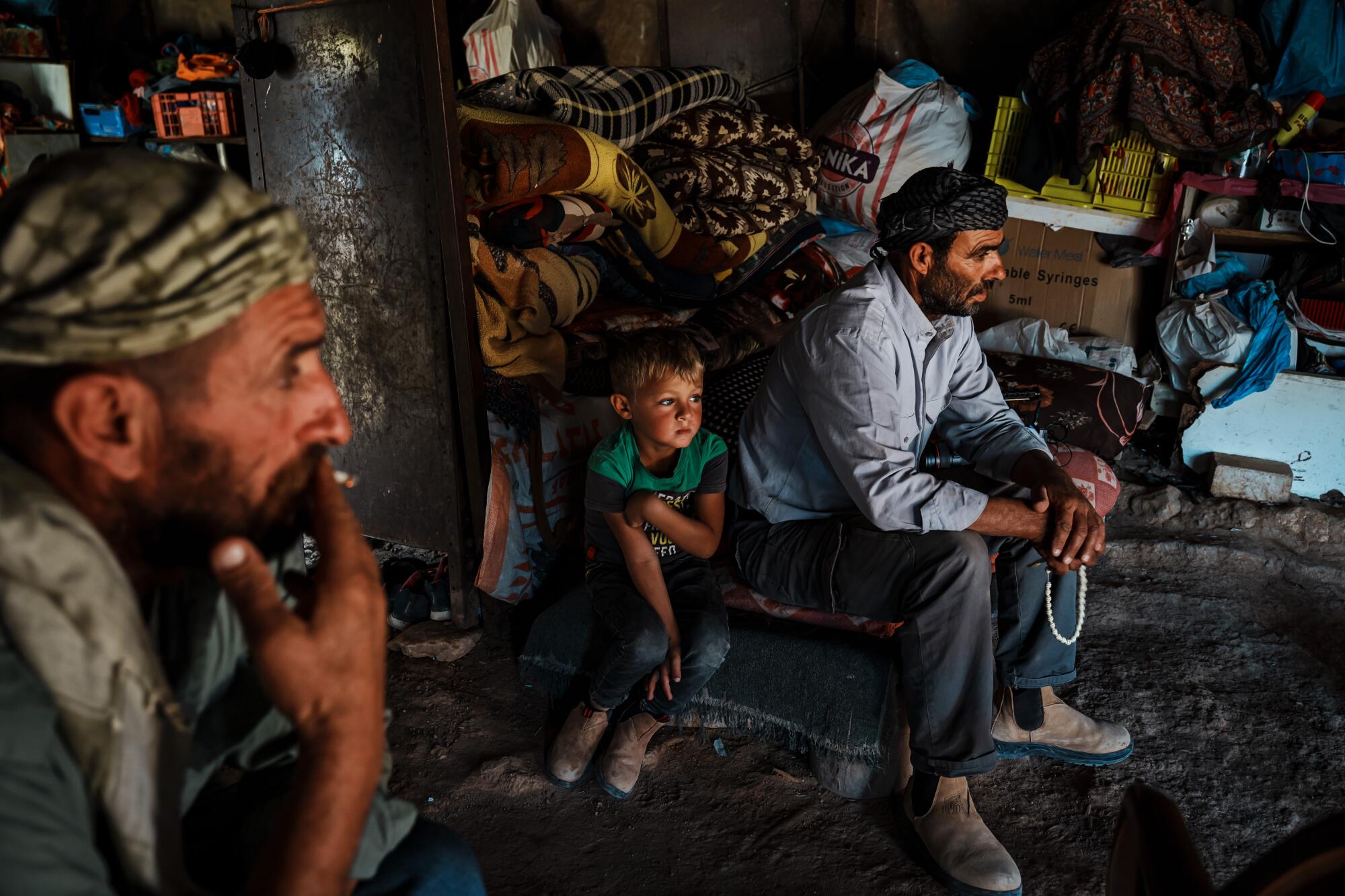 Bassam Alzaarir, 55, sits with his son Amer, in Wadi Tiran.