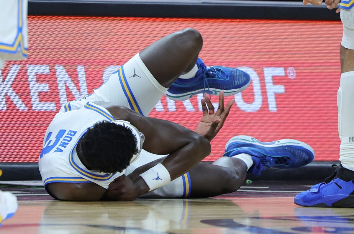 UCLA's Adem Bona asks the coaches for help after being injured diving for a loose ball against Oregon.