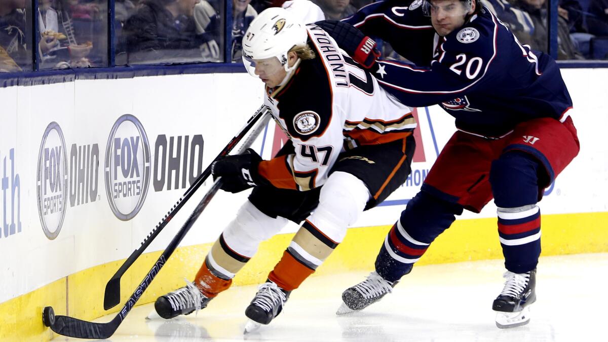 Ducks defenseman Hampus Lindholm tries to clear the puck while pressured by Blue Jackets winger Brandon Saad during their game Thursday night.