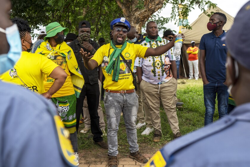 An African National Congress party (ANC) supporter who could not access the party's 110th birthday celebration at Polokwane's Peter Mokaba stadium argues with police Saturday Jan. 8, 2022. Because of coronavirus regulations, only 2000 could attend the anniversary , amid deep divisions, graft allegations and broad challenges that saw the ANC perform dismally in local government elections last year. (AP Photo/Jerome Delay)