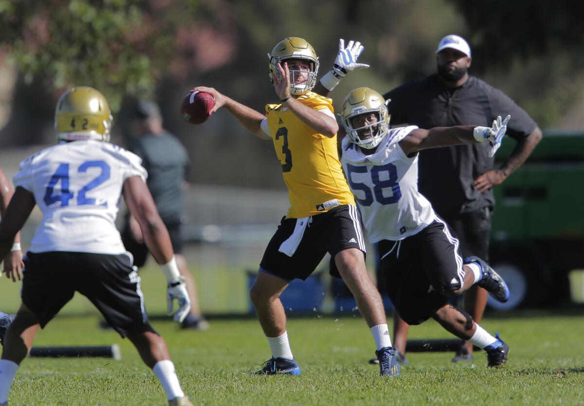 Freshman quarterback Josh Rosen looks for an open receiver as linebacker Dean Hollins rushes in Aug. 10, the first day of UCLA training camp at Cal State San Bernardino.