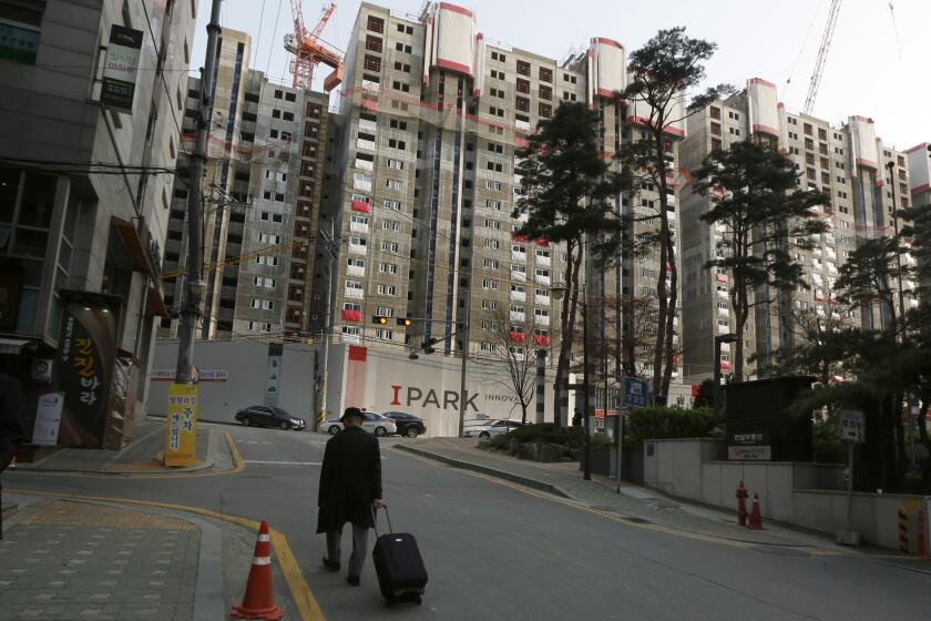 A man walks down the street in front of a background of high-rise buildings in Seoul's Gangnam district, in South Korea Wednesday, April 17, 2013. (AP Photo/Kin Cheung)