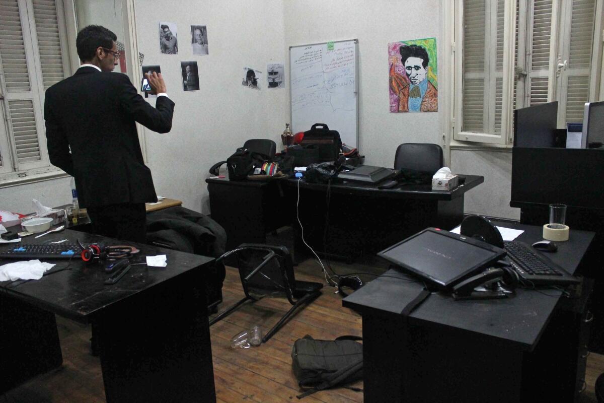 A man takes pictures of the offices of the Egyptian Center for Economic and Social Rights in Cairo following an overnight raid by police.