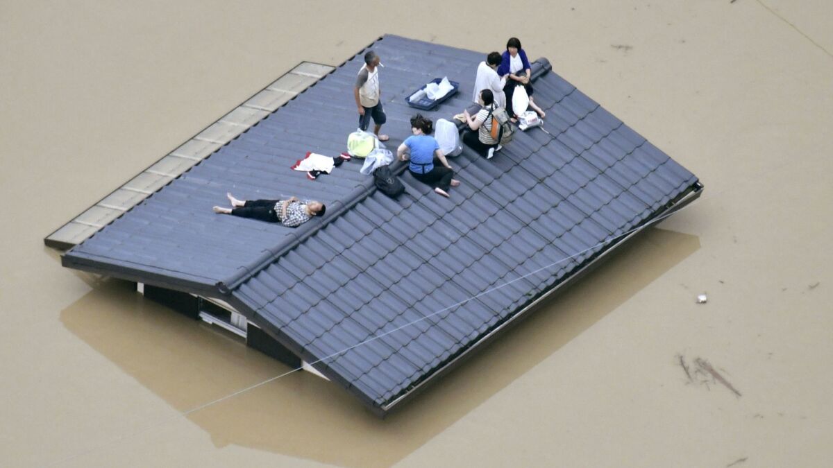 People wait Saturday to be rescued from a rooftop as heavy rains cause flooding in Kurashiki, Okayama prefecture, southwestern Japan.
