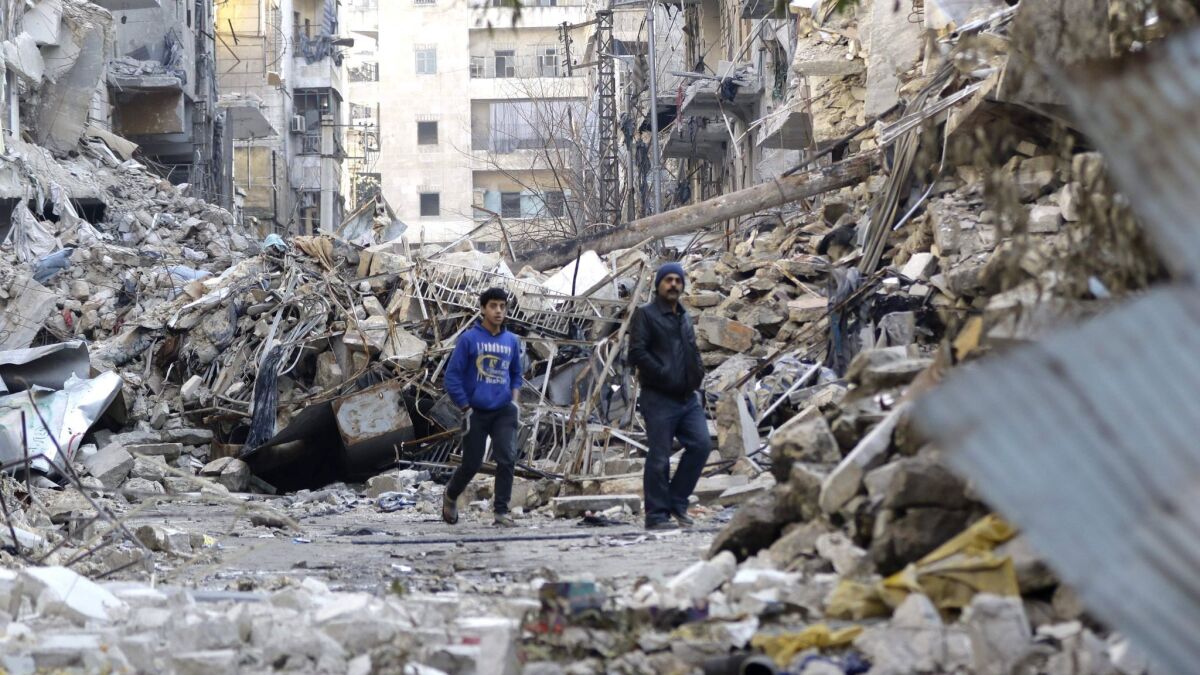 Two people walk amid destroyed buildings in Aleppo, Syria's formerly rebel-held al-Shaar neighborhood, on Jan. 21, 2017.