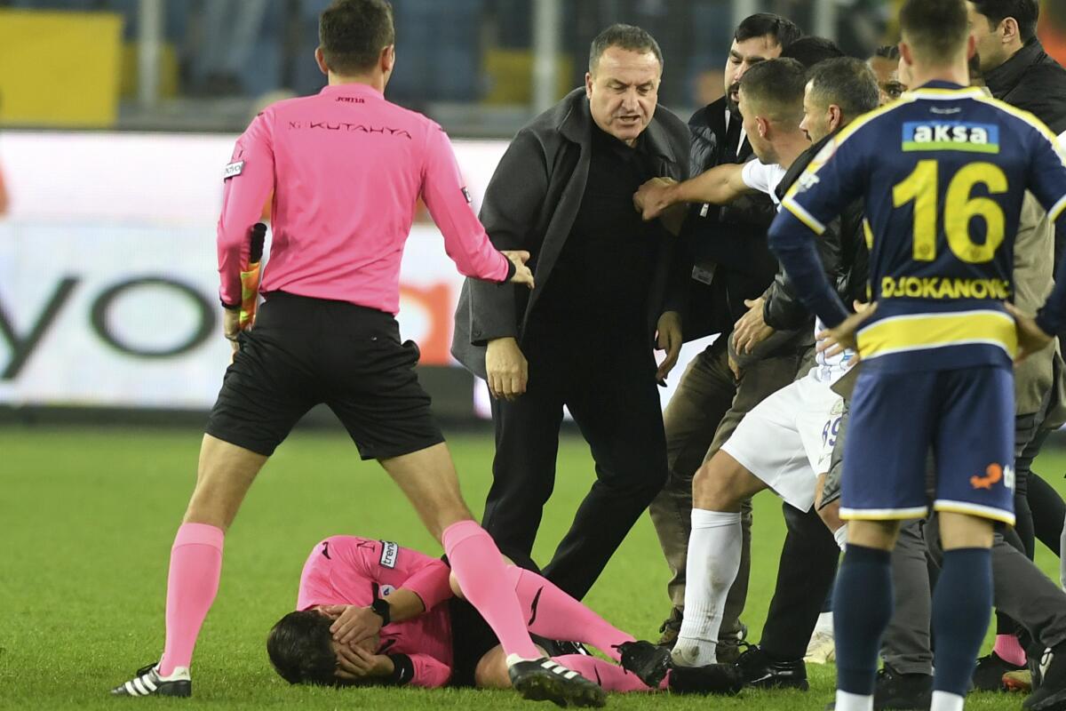 En esta imagen de archivo, el árbitro Halil Umut Meler se sujeta el rostro mientras está tirado sobre el piso