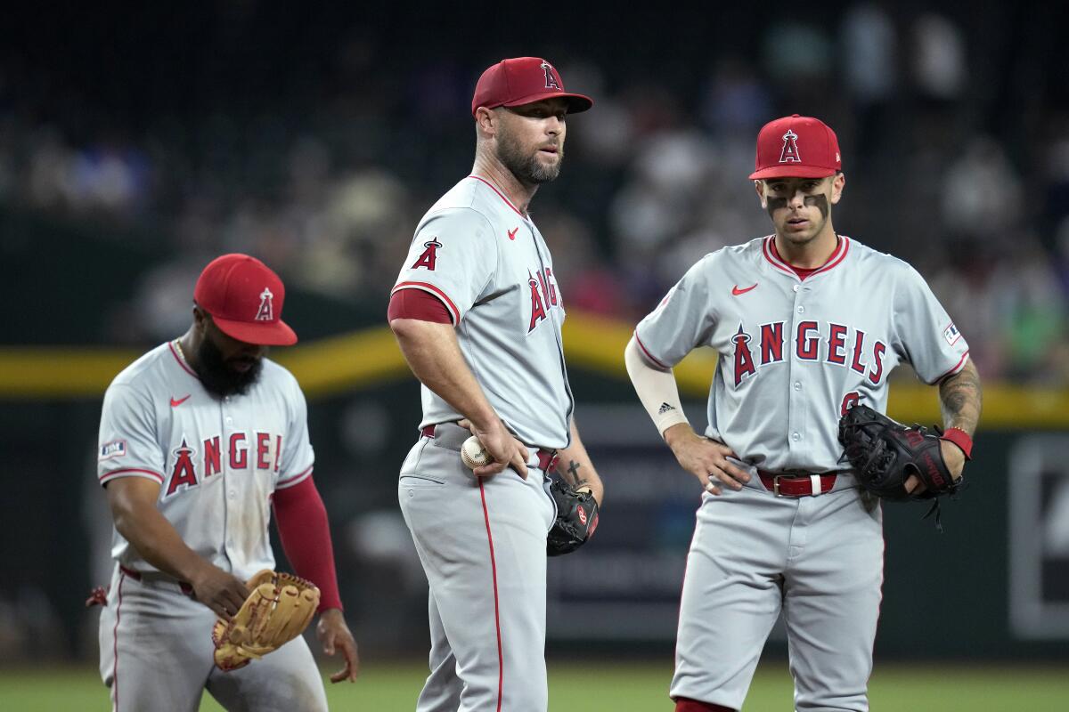 Angels pitcher Hunter Strickland pauses on the mound in front of third baseman Luis Rengifo and shortstop Zach Neto 