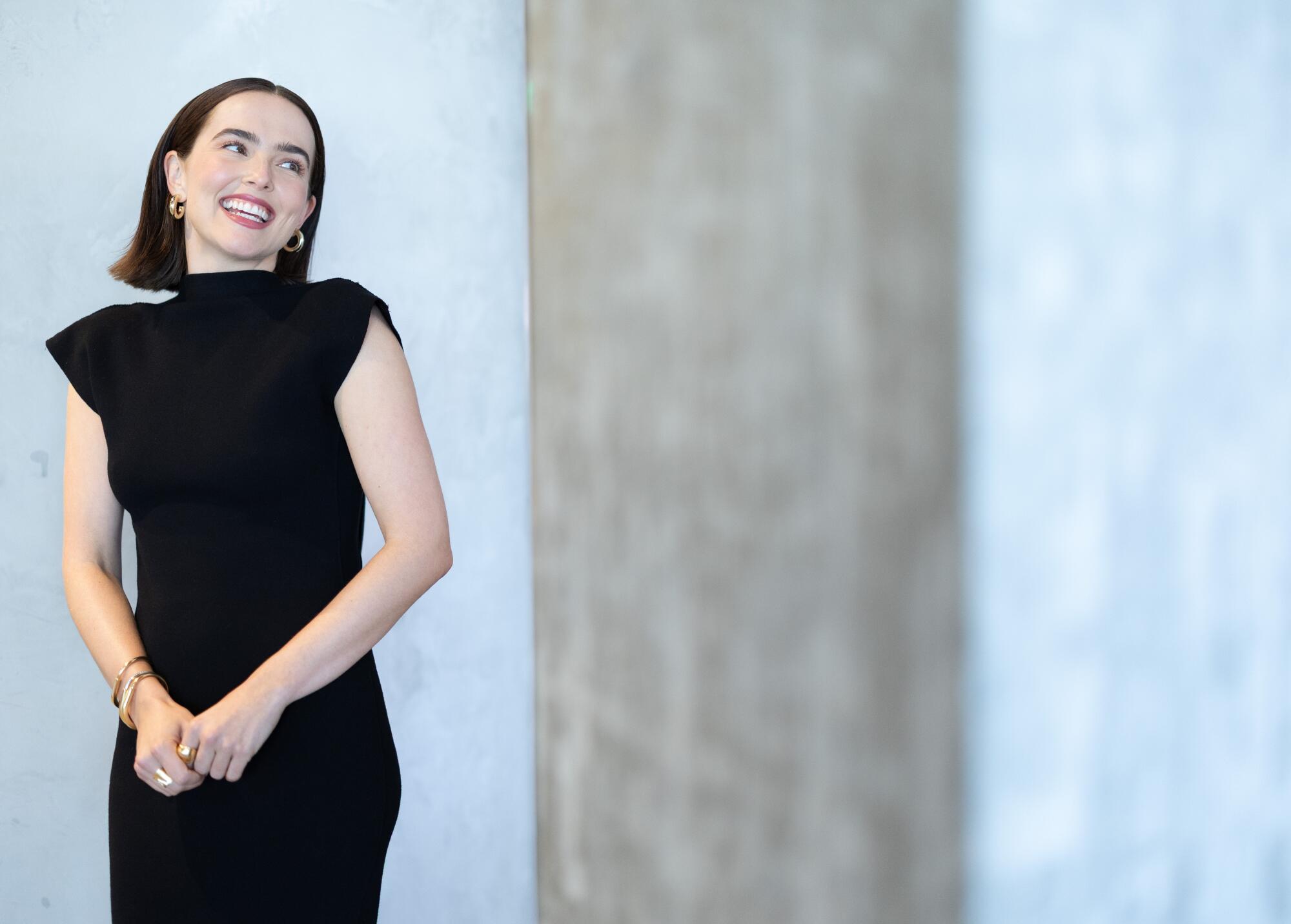 A woman in a black dress smiles.