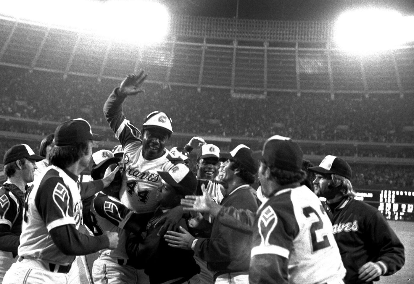 Teammates extend their congratulations as they greet Hank Aaron of the Atlanta Braves at home plate