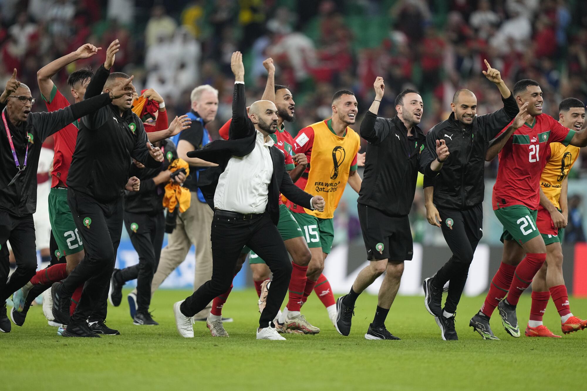 Morocco coach Walid Regragui, front, and his players and staff celebrate after beating Portugal