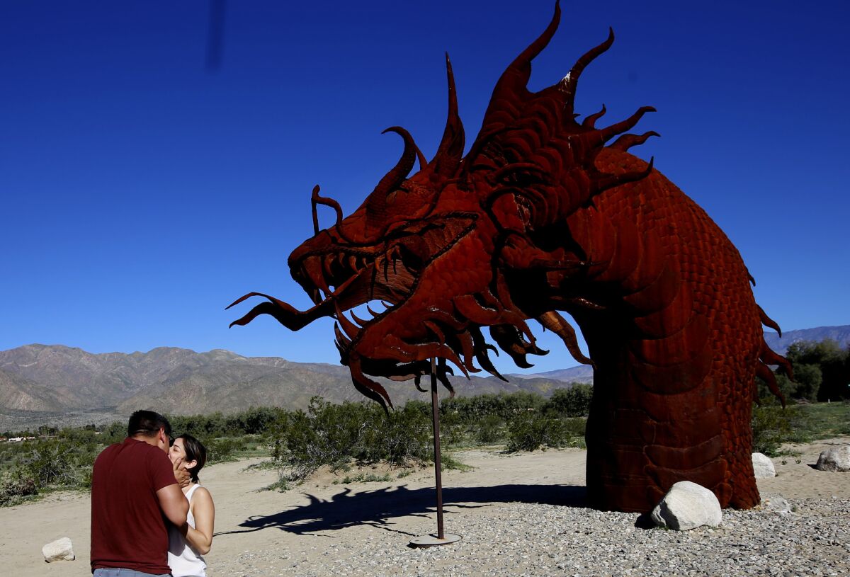 David Jacobson, of Hollywood, kisses Daisy Gonzalez, of La Mirada, next to the the dragon sculpture in Anza Borrego Desert State Park in San Diego County.