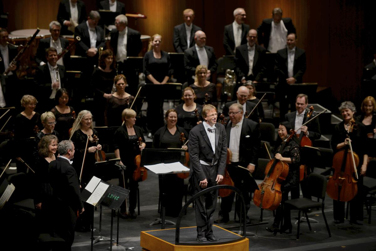 Long Beach Symphony music director Eckart Preu faces the audience with an orchestra behind him
