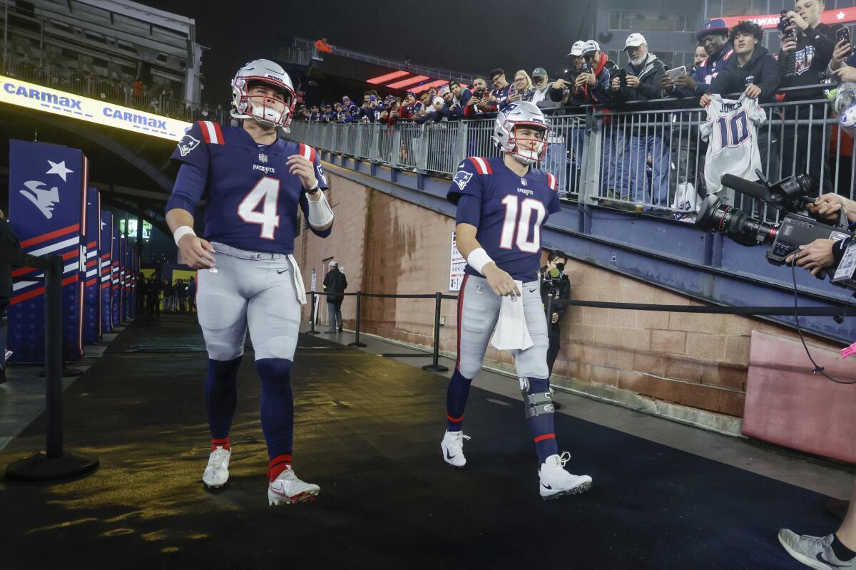 New England Patriots quarterbacks Bailey Zappe and Mac Jones walk out of the tunnel before a game.