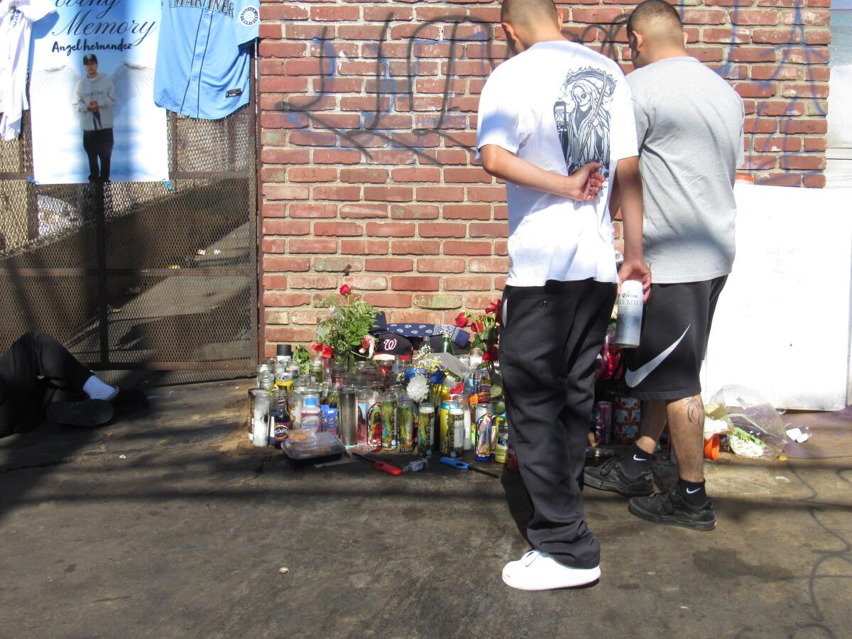 Visitors pay respects at a memorial outside a liquor store on Costa Mesa's Placentia Avenue.