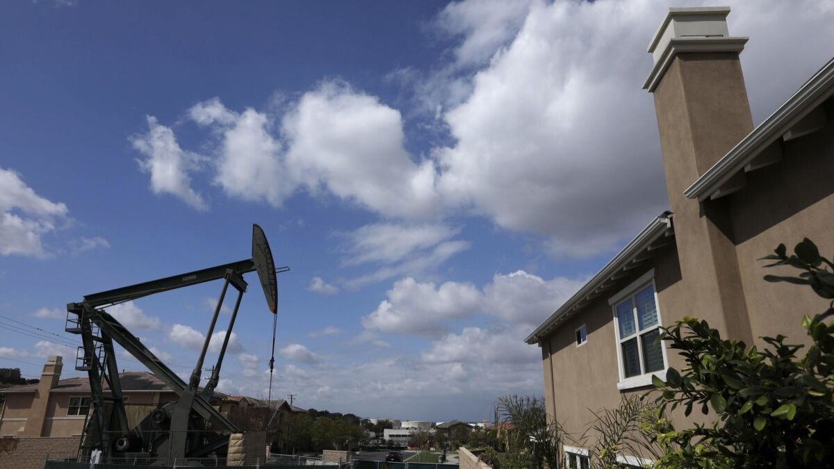 A pumpjack, or nodding donkey, stands near a home on 20th Street at Obispo Avenue in Signal Hill on April 16.