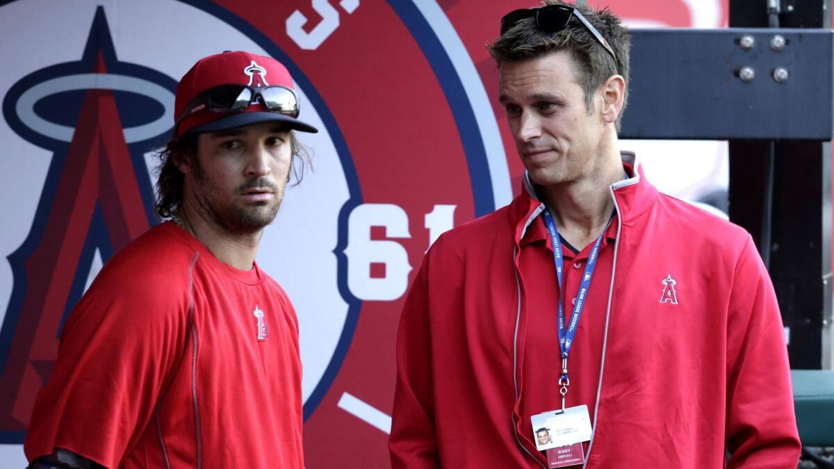 Angels General Manager Jerry Dipoto, right, talks with starting pitcher C.J. Wilson before a game against the Kansas City Royals on April 11.