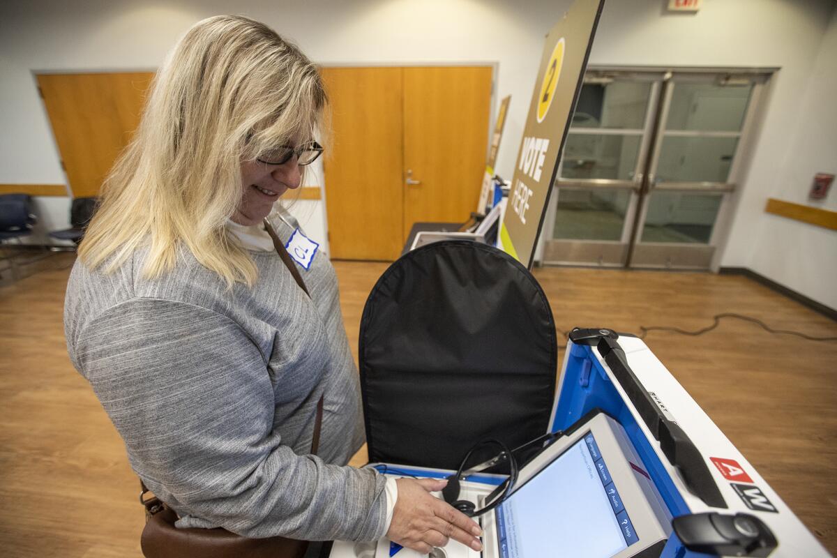 Catherine Miller casts a mock vote on a voting machine during a presentation Wednesday at the Costa Mesa Senior Center about changes to voting systems that begin with this year's California primary election.