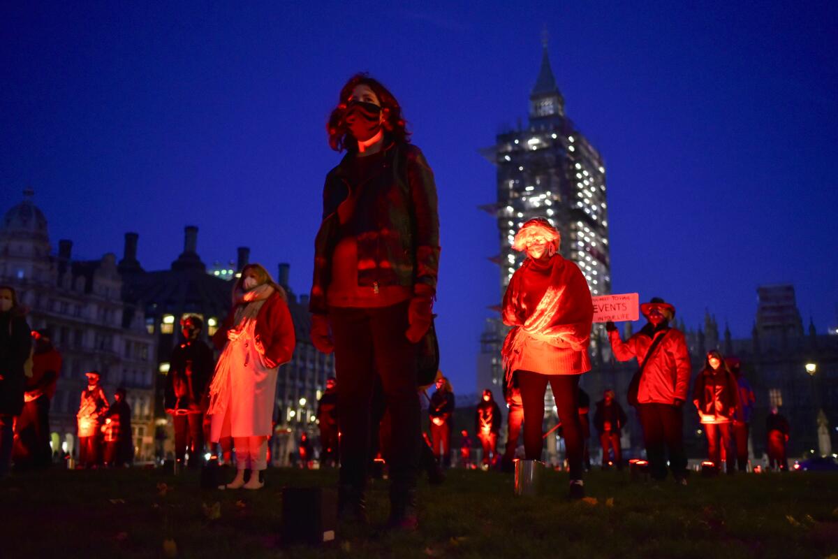Arts and hospitality workers idled by the pandemic stand six feet apart during a silent vigil in Parliament Square in London