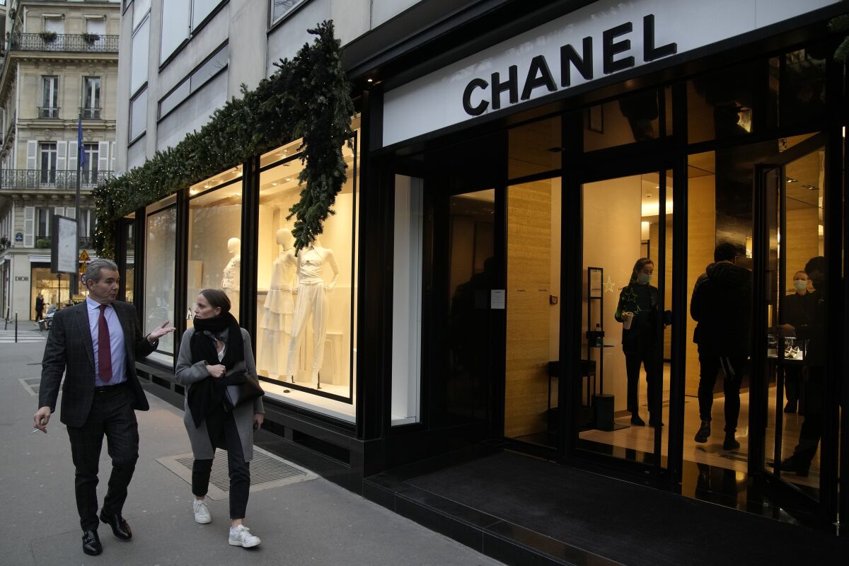 People walk past a Chanel boutique Wednesday, Dec. 15, 2021 in Paris. The French luxury fashion house Chanel has chosen Leena Nair, an industry outsider from India and longtime executive at Unilever, to be its new CEO. (AP Photo/Christophe Ena)