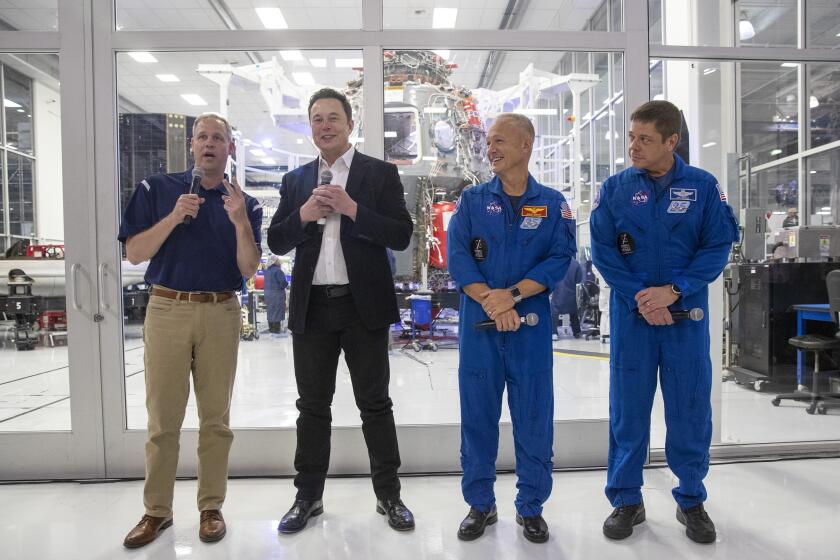 HAWTHORNE, CALIF. -- THURSDAY, OCTOBER 10, 2019: From left, NASA Administrator Jim Bridenstine, SpaceX CEO Elon Musk, NASA astronauts Doug Hurley and Bob Behnken talk with reporters at a press conference in front of the SpaceX clean room where the Dragon Crew capsule is assembled in Hawthorne, Calif., on Oct. 10, 2019. (Brian van der Brug / Los Angeles Times)