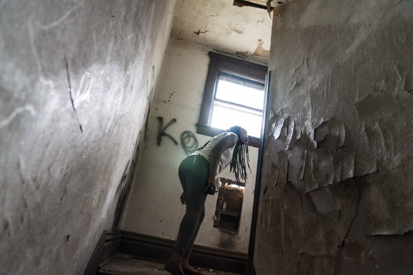 Larrecsa Cox, who leads the Quick Response Team whose mission is to save every citizen who survives an overdose from the next one, peers around a stairwell while walking through an abandoned home frequented by people struggling with addiction, in Huntington, W.Va., Thursday, March 18, 2021. As the COVID pandemic killed more than a half-million Americans, it also quietly worsened what was before it the country's greatest public health crisis: addiction and despair. (AP Photo/David Goldman)