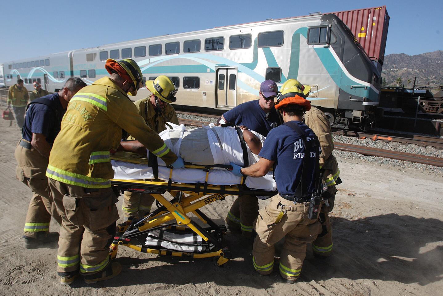 A fifth victim, of six, is taken by gurney to an awaiting ambulance from a southbound MetroLink commuter train after hitting a motorist at the intersection of San Fernando and Buena Vista in Burbank on Monday, September 2, 2014. There was one driver taken to the hospital in critical condition.