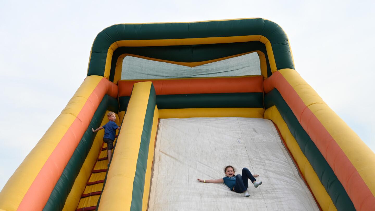 Parker Ginter of Hunterstown, Pa., left, looks back as his sister Haven slides past on an inflatable ride during the carnival at the Harney Volunteer Fire Company on Tuesday, June 25.