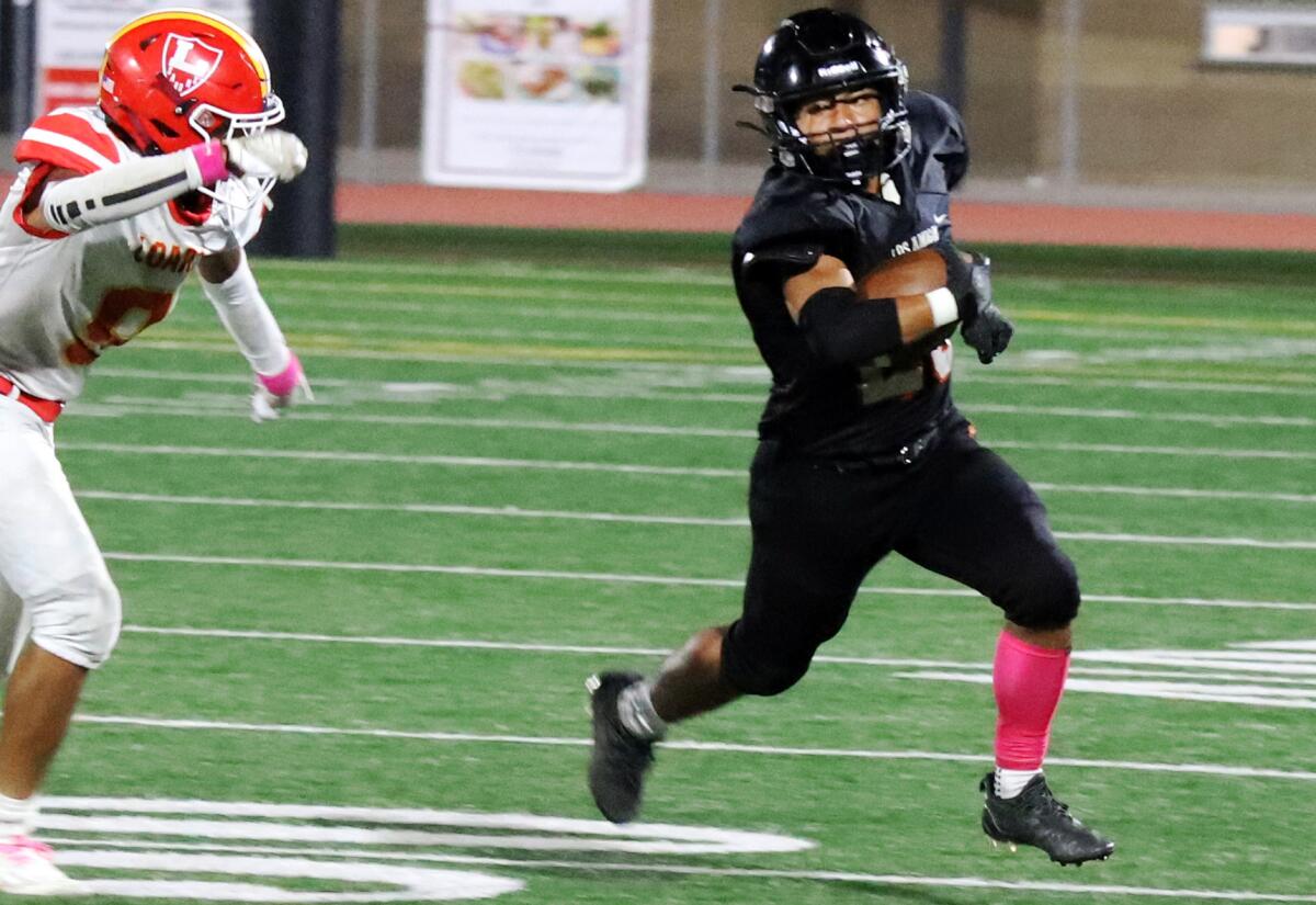 Los Amigos' Pedro Hernandez (23) runs around Loara's defensive line in a Garden Grove League game on Thursday.