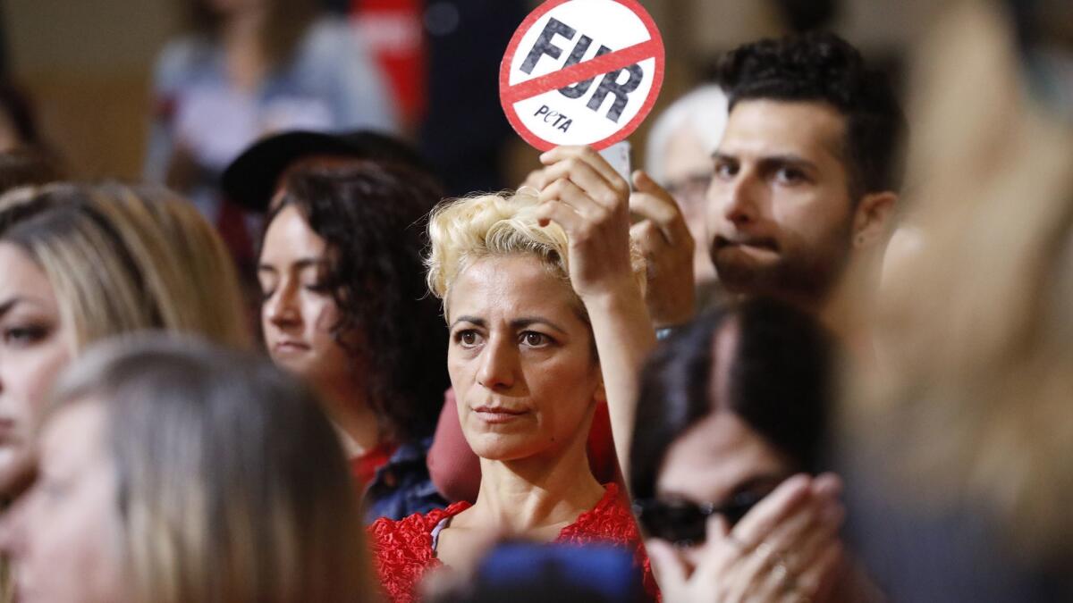 Emek Echo holds a "No fur" sign during the Los Angeles City Council meeting.
