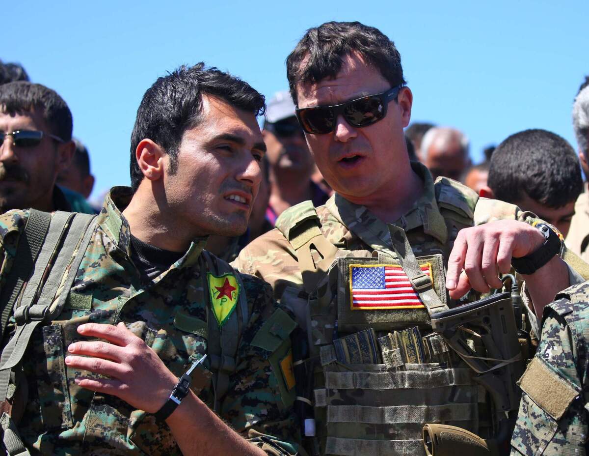 A U.S. officer talks with a fighter from the Kurdish People's Protection Units, or YPG, at the site of Turkish airstrikes in northeastern Syria in April 2017.