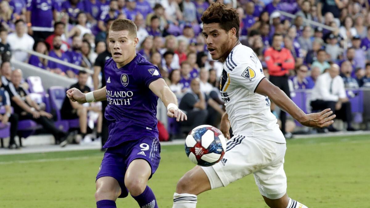 Orlando City's Chris Mueller (9) takes a shot past Galaxy's Jonathan dos Santos during the first half on Friday in Orlando, Fla.