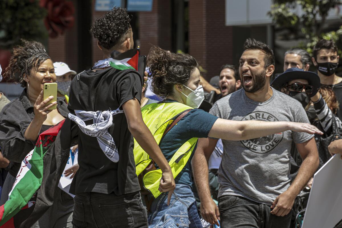 A person separates two people in a shouting match at a protest