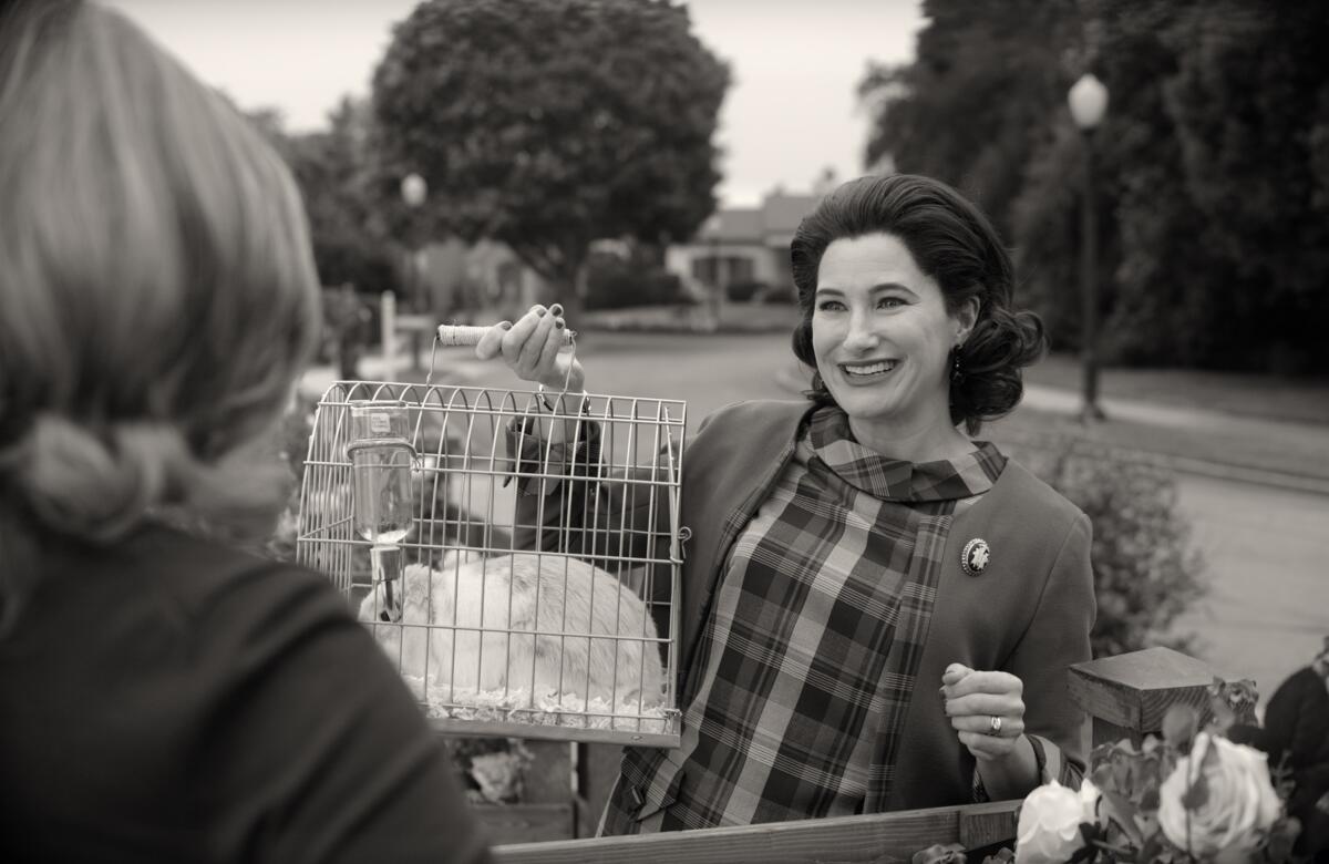 A woman holds up a cage containing a rabbit