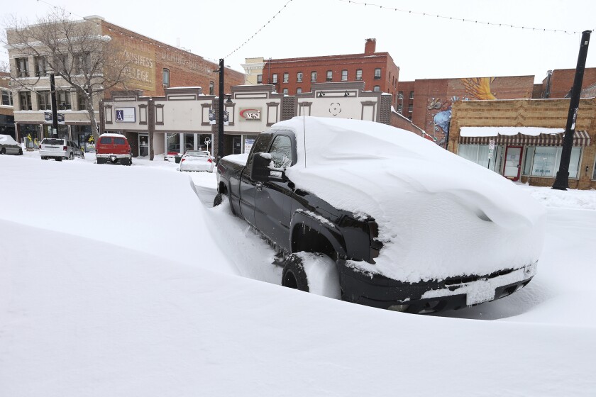 A pickup truck sits covered in snow Monday in downtown Cheyenne, Wyo.