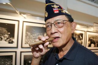 FILE - Former Philippine President Fidel Ramos bites his cigar as he looks on photographs during an exhibit on the 20th anniversary of "People Power" in suburban Makati, south of Manila, Philippines, on Feb. 22, 2006. Ramos, a U.S.-trained ex-general who saw action in the Korean and Vietnam wars and played a key role in a 1986 pro-democracy uprising that ousted a dictator, has died. He was 94. Some of Ramos's relatives were with him when he died on Sunday, July 31, 2022, said his longtime aide Norman Legaspi. (AP Photo/Aaron Favila, File)